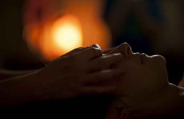 Massaggio viso in cabina a luce soffusa con candela